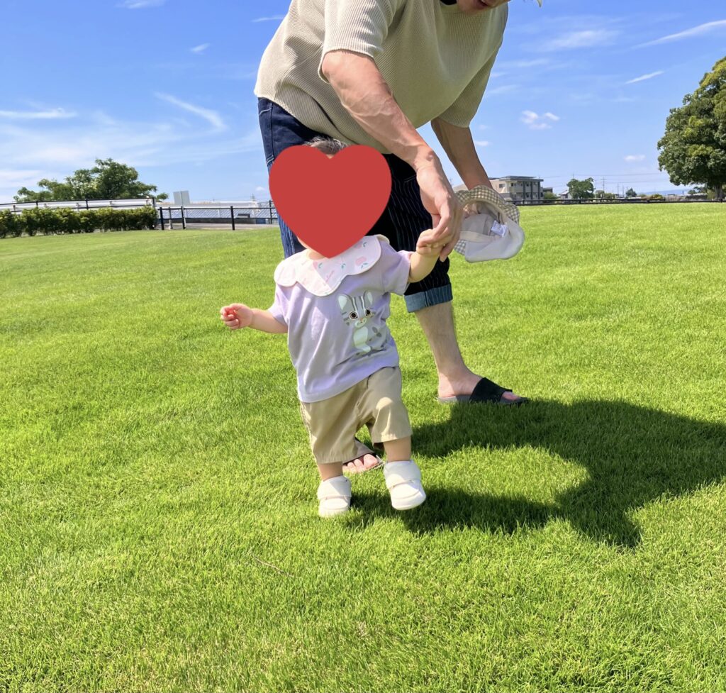 イフミ―のファーストシューズを履いて芝生を歩く子どもと父親